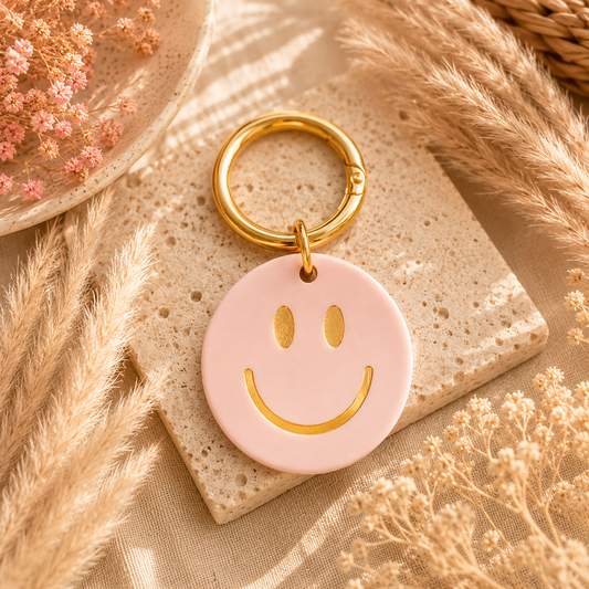runder Smilie-schlüsselanhänger in pastellrosa und goldfarbenem Ring. Perfekt als Geschenkidee.
